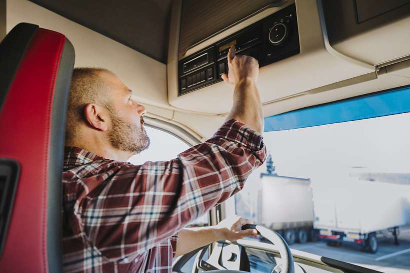 Lkw-Fahrer zeigt auf im Lkw verbauten inteligenten Fahrtenschreiber 2. Generation