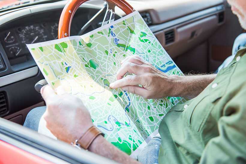 conductor planifica ruta con atlas de carreteras